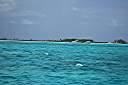 Anegada from one half mile out through a telephoto lens. It is what you would see with a good pair of binoculars. The red entrance buoy is visible in the center, just below the beach.