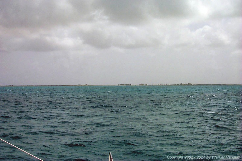 Approaching Anegada. It is slightly hazy and we are 1 mile from the entrance buoys. You can see Pomato Point (the two small trees on the left), the Australian pines at Setting Point Villa, the palm trees at Neptune's Treasure, the white roof of Neptune's Treasure, the Australian pines at Whistling Pines, the Lobster Trap Restaurant, the Australian pines at Setting Point, Potter's by the Sea, and the bonefish flats to the east of Setting Point.