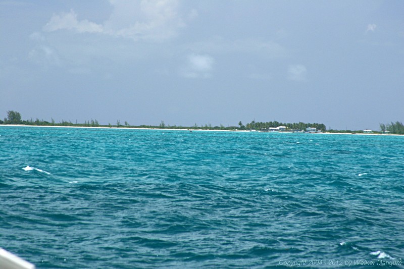 Anegada from one mile out through a telephoto lens. It is what you would see with a good pair of binoculars. The red entrance buoy is visible in the center, just below the beach.