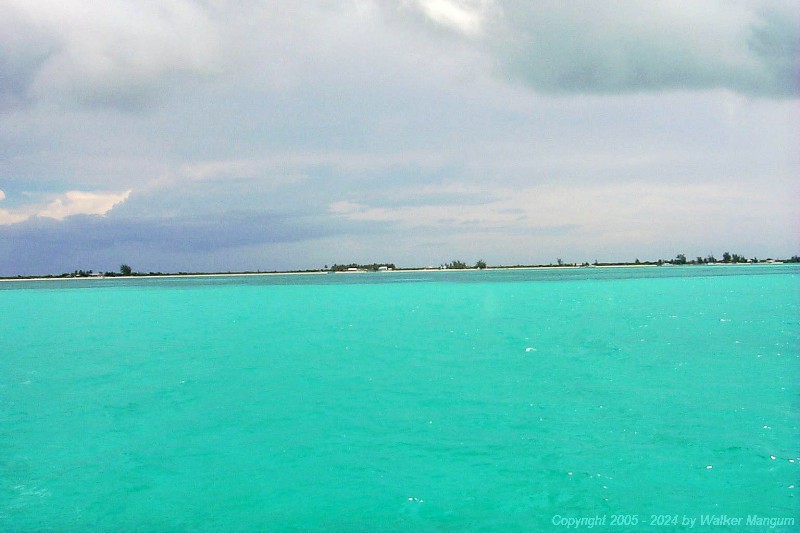The Anegada shoreline after entering the entrance channel.
The flat-topped group of trees is now completely visible, with the white roof of Neptune's Treasure in front, and the Anegada Reef Hotel visible at the far right.